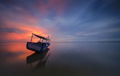 Fishing boat in sea against sky during sunset