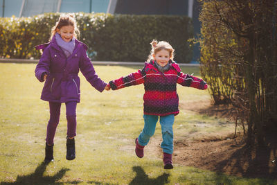 Full length of happy girls running on field