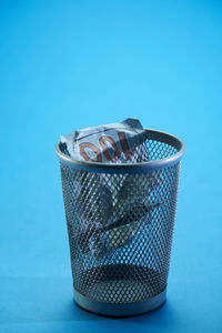 Close-up of garbage bin on table against blue background
