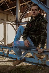 Portrait of young man sitting on metal