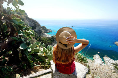 View of woman sitting on wall in capo vaticano
whit lookout of the coast of the gods, calabria,italy