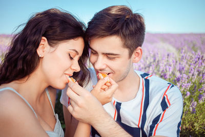 A young girl and a guy feed each other an orange