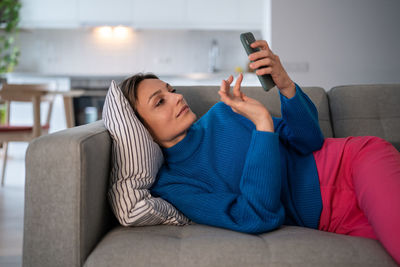 Attractive woman lay down on sofa pillow using smartphone web surfing. internet connection concept.