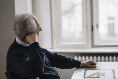 Senior man at home thinking with architectural plan on table