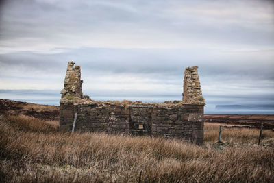 Old ruin on field against sky