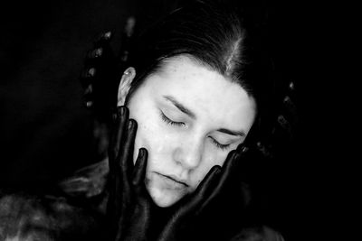 Close-up of young woman with eyes closed on black background