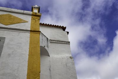 Low angle view of cross by building against sky