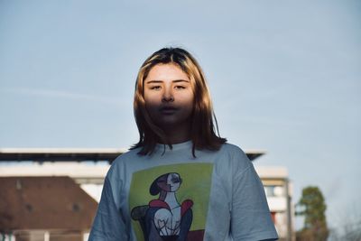 Portrait of teenage girl looking away against sky