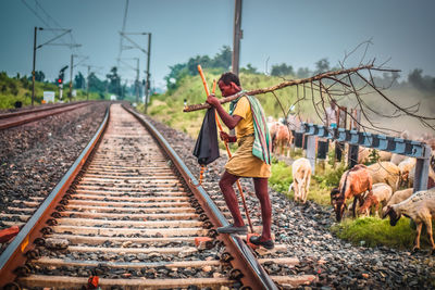 Man carrying dead tree on railroad track