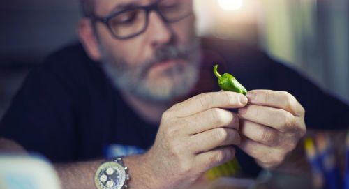 Close-up of man looking at chili pepper