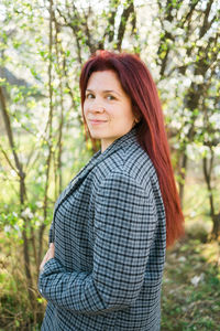 Young woman standing against trees