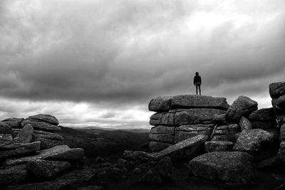 Rear view of man standing on rock against sky