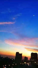 Illuminated cityscape against sky during sunset