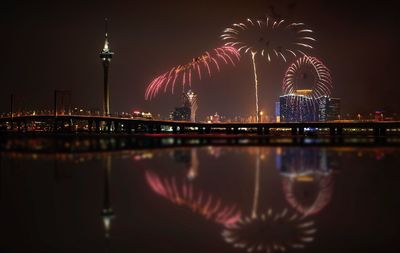 Firework display over river and buildings at night