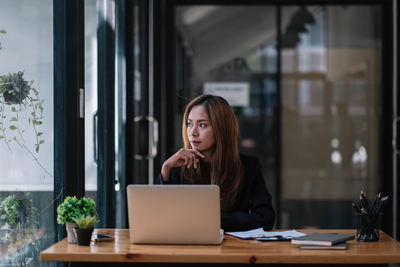 Young businesswoman looking away sitting at office