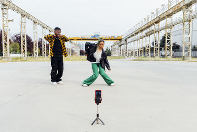 Young woman filming dance video through smart phone on footpath