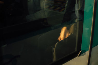 Midsection of man sitting in bus seen through glass window