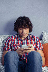 Close-up of man using mobile phone while sitting on bed at home