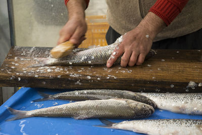 Midsection of man preparing fish on table