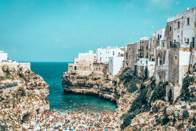 Buildings by sea against blue sky