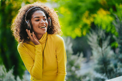 Happy young woman enjoying music in park