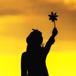 Silhouette woman against orange sky