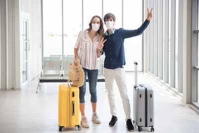 Couple man and woman wearing face masks standing with luggage in the airport