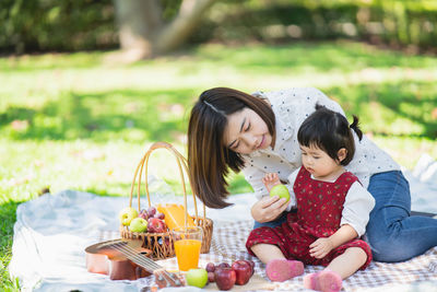 Portrait of smiling mother and daughter sitting at park