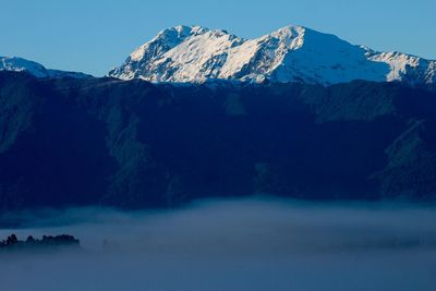 Fog over snowcapped mountain range