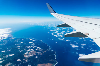 Airplane wing over landscape and sea against sky