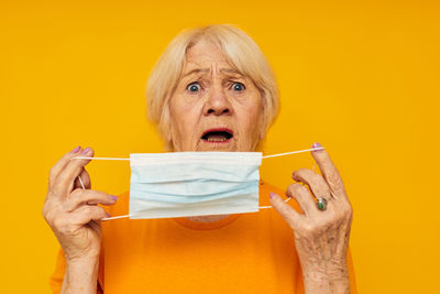 Close-up of woman holding gift against yellow background