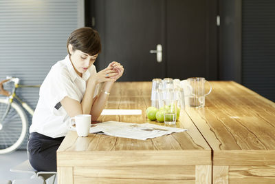 Woman reading newspaper at wooden table in a modern canteen