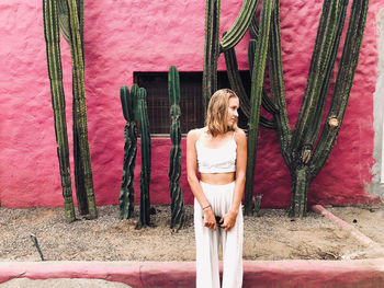 Woman wearing white standing next to the pink wall