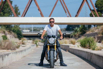 Portrait of man riding bicycle on bridge