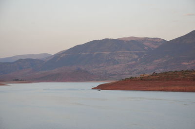 Scenic view of sea and mountains against clear sky