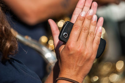 Cropped image of woman with mobile phone clapping outdoors