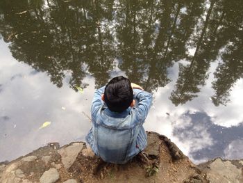 Rear view of boy crouching by lakeshore