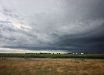 Scenic view of field against storm clouds