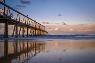 Pier over sea against sky during sunset