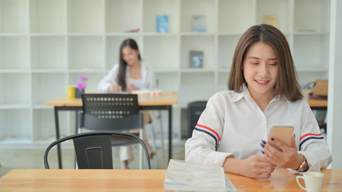 Portrait of a smiling young woman sitting on table