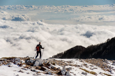 Man standing on snowcapped mountain against sky