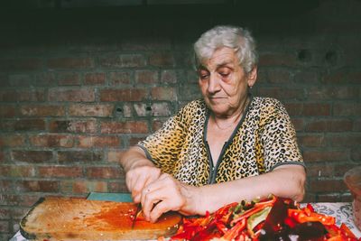 Mid adult woman holding ice cream on table against brick wall