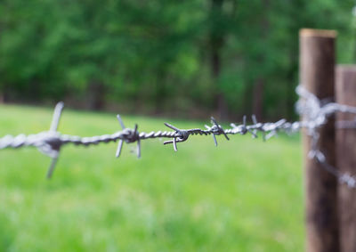 Close-up of barbed wire fence over field