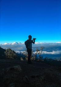 Man standing on mountain against blue sky