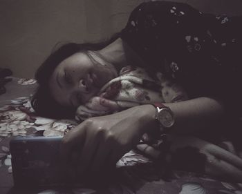 Young woman using phone while lying on bed at home