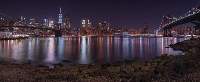 Brooklyn and manhattan bridge over east river against sky in city at night