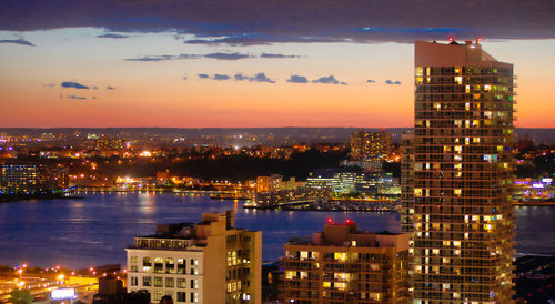 Illuminated buildings in city against sky at sunset