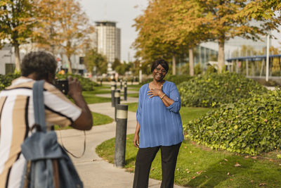 Man photographing woman through camera standing in park