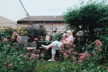 WOMAN STANDING BY FLOWERS AGAINST TREES