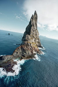 Rock formation on sea shore against sky